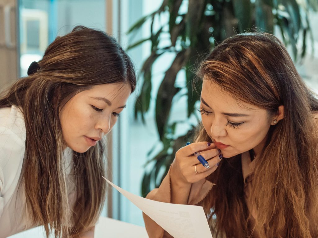 Two women collaborating in an office setting, focusing on documents.